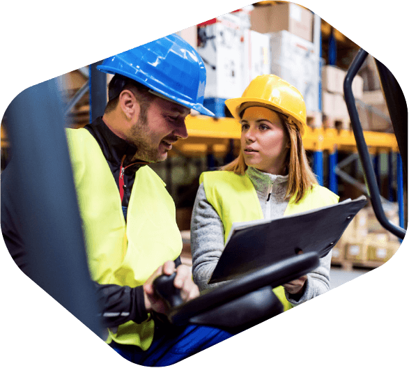 Man and Woman Working Next to Each Other in Factory Looking at SOP