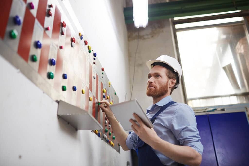 Employee Wearing Hard Hat Holding Tablet while Working in Factory