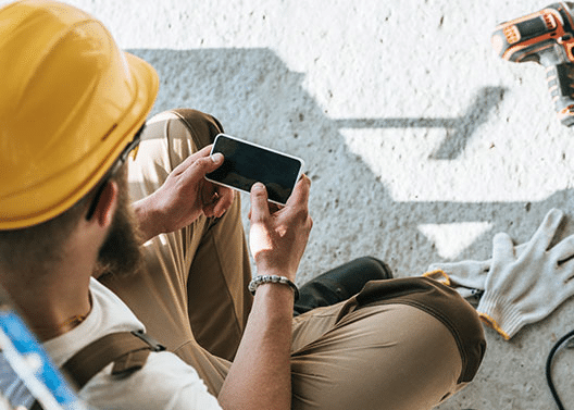 Male Construction Worker Staying Connected with Project Updates on Mobile Phone - iTacit