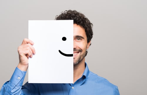 Smiling male employee holding paper with smiley face