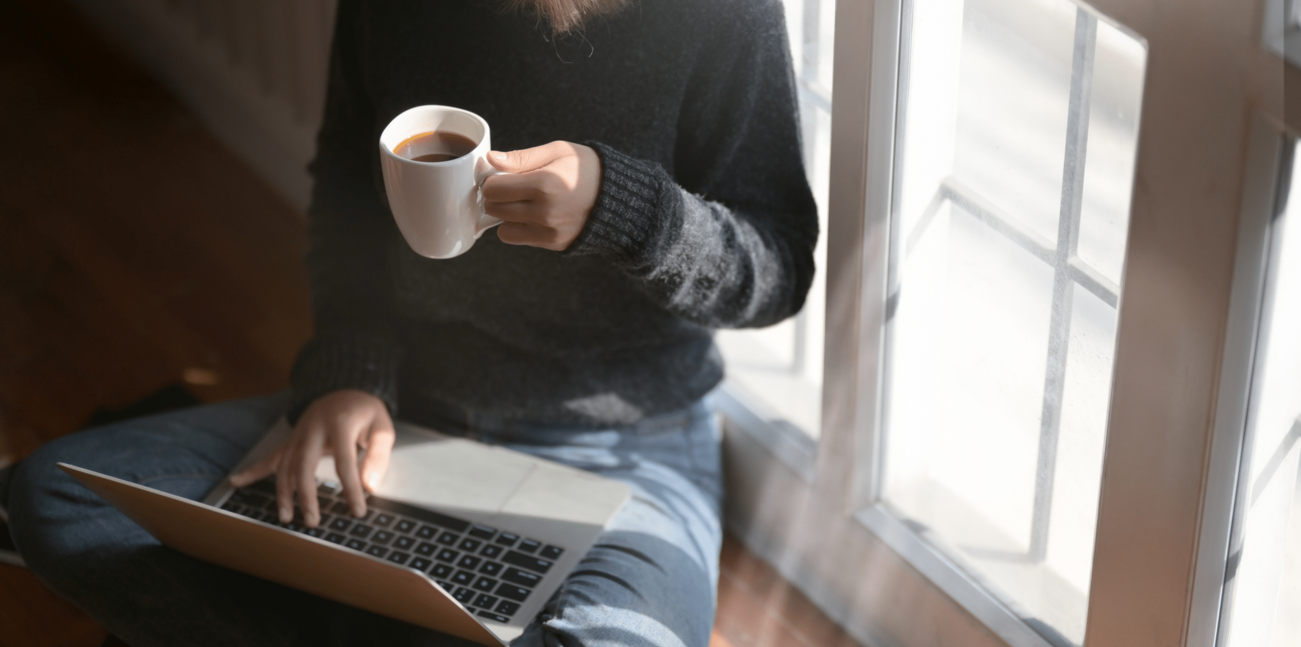 Woman working at home with a coffee cup in hand