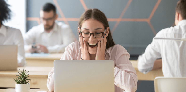 Woman behind laptop in co-working place looking excited