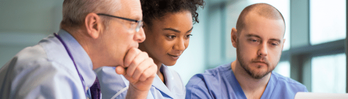 a female nurse and 2 men healthcare professionals looking at a computer screen